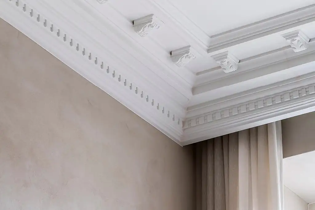 Salón elegante con elementos decorativos arquitectónicos en pared y techo, como cornisas y molduras.